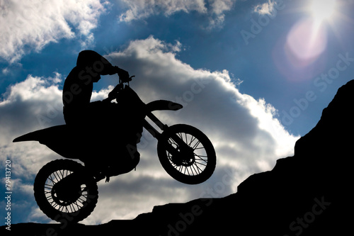 Motocross - silhouette with a rock and blue sky with sun