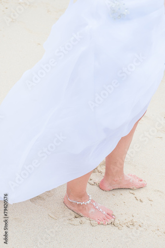 bride is wearing beautiful barefoot sandals in beach wedding cer photo