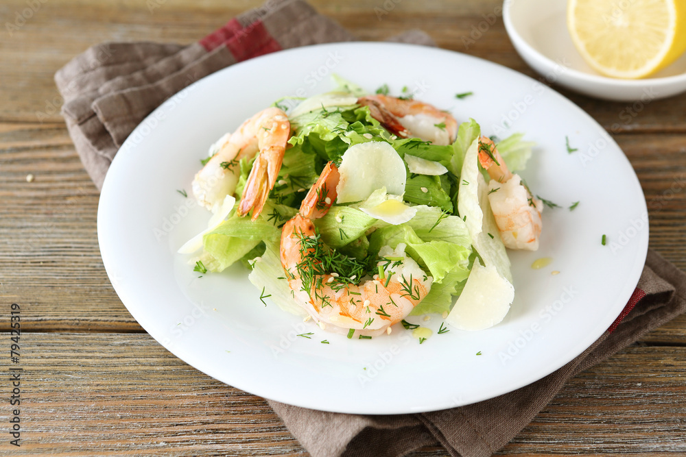 Salad with shrimps, lettuce and cheese on a white plate