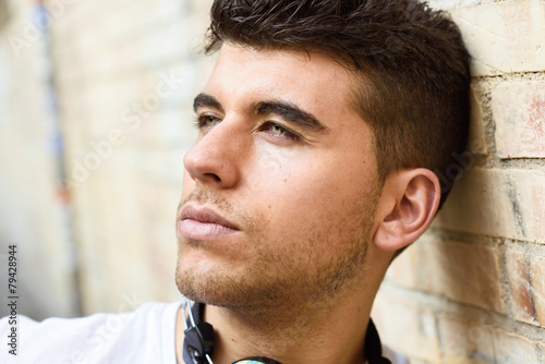 Photography Handsome young man with blue eyes posing near a wall