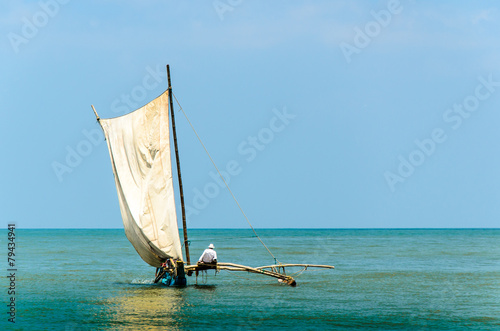 Segelboot mit Mann segelt vor Küste