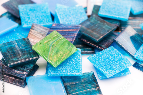 Stack of blue and green glass mosaic tiles on white background
