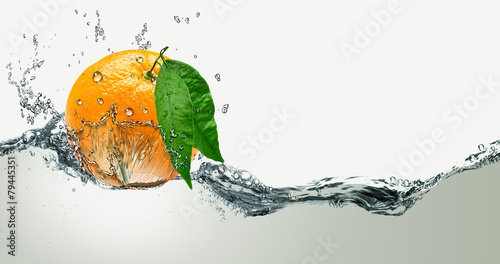 Schilderij op canvas Orange with green leaves on a background of splashing water.