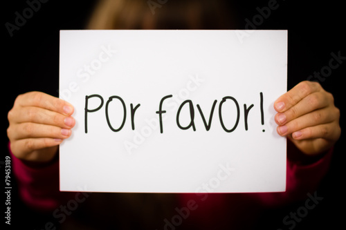 Child holding sign with Spanish words Por Favor - Please