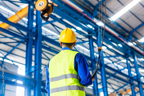Worker in factory controlling crane with remote