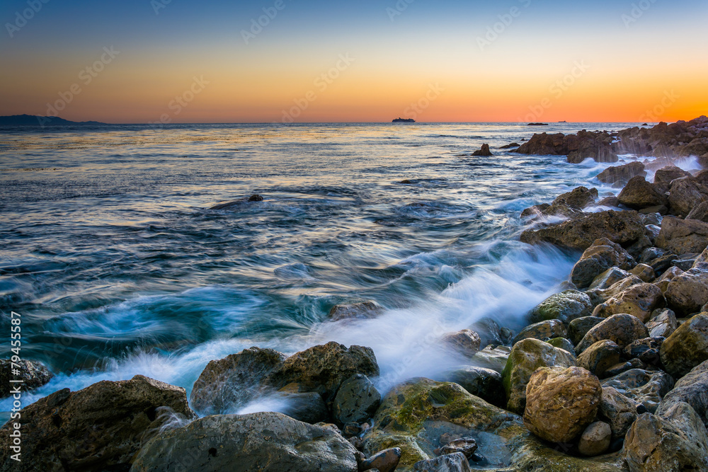 Waves crashing on rocks at Pelican Cove at sunset, in Rancho Pal