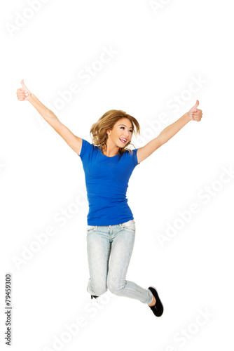 Young happy woman jumping with thumbs up.