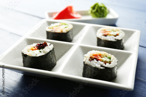 Vegetable sushi rolls on plate on color wooden background