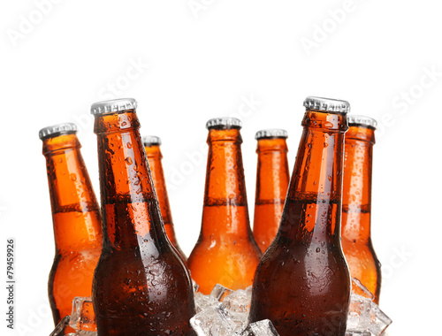 Glass bottles of beer in ice cubes isolated on white