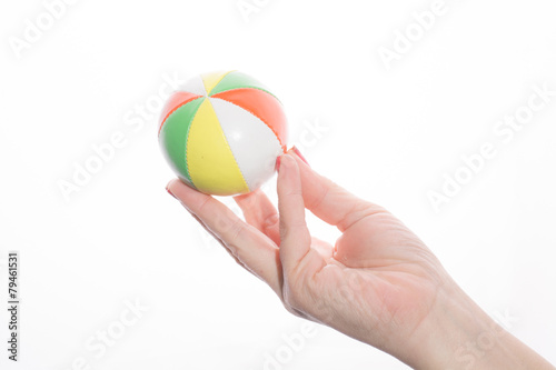 female hand holding colored juggling balls on a white background