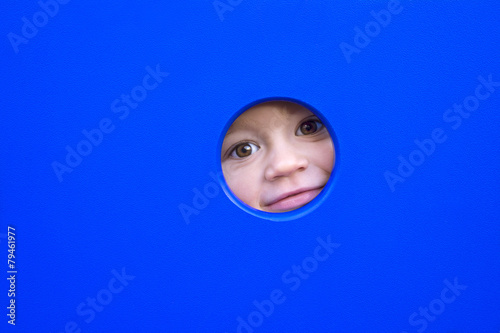 little kid playing peek-a-boo on a playground