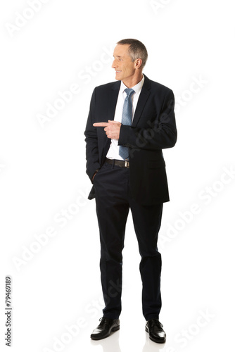 Full length businessman pointing to the left