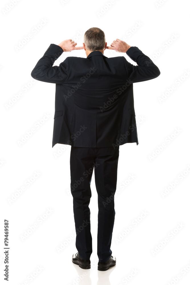 Businessman plugging his ears Businessman plugging his ears