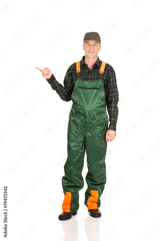 Mature gardener in uniform pointing to the left Mature gardener in uniform pointing to the left