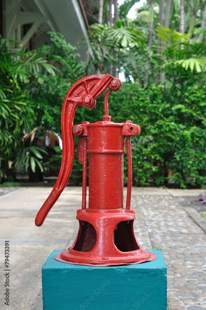 Red hand manual water pump in garden Red hand manual water pump in garden