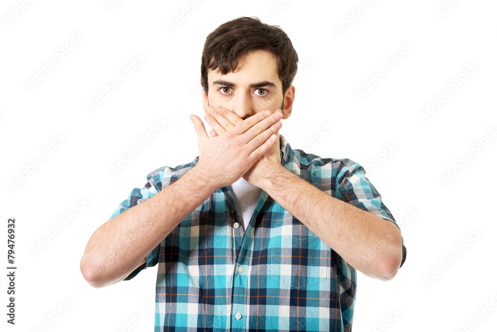 Young shocked man covering his mouth.