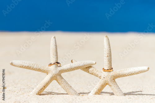 wedding rings on sand and starfish, outdoor beach wedding photo