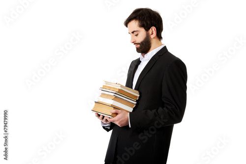 Young businessman holding stack of books.