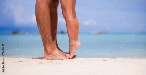 Close up kid's and male feet at white sandy beach