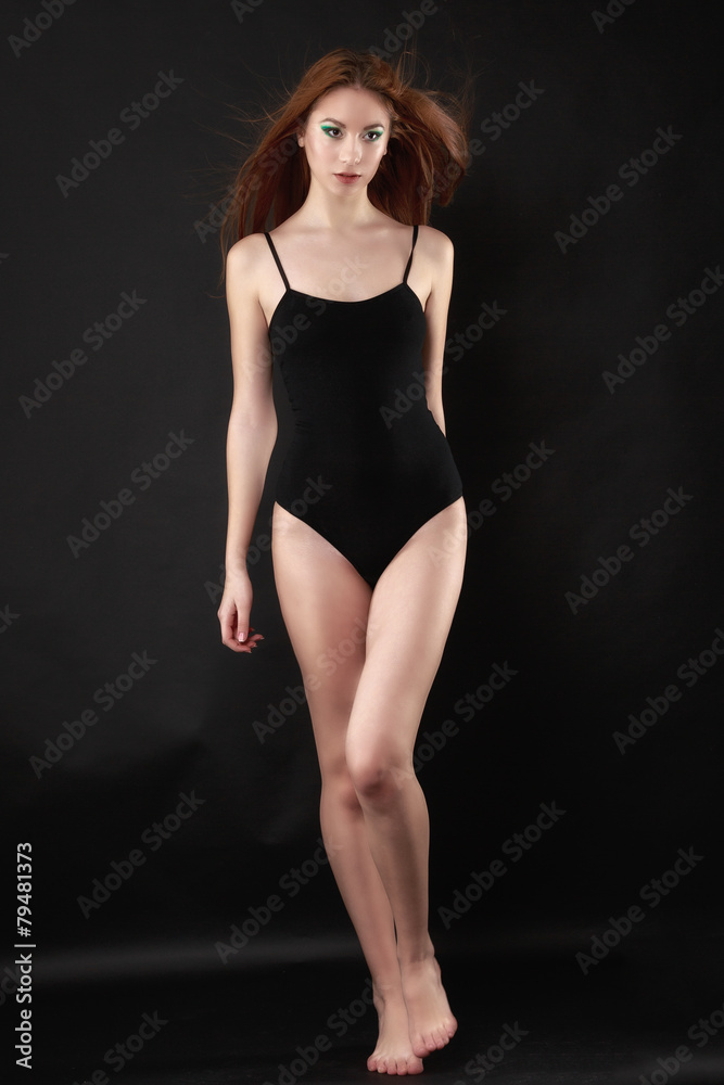 Beautiful woman in a black bodysuit posing on a black background