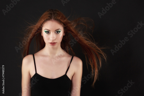 Beautiful woman in a black bodysuit posing on a black background