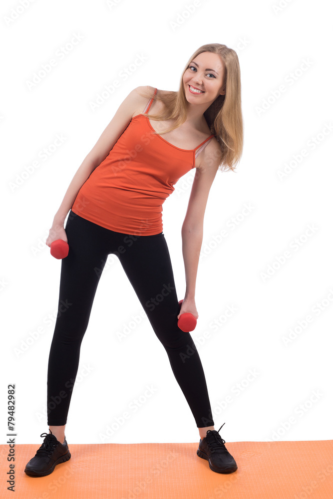 Beautiful woman in sportswear exercising with the red dumbbells.
