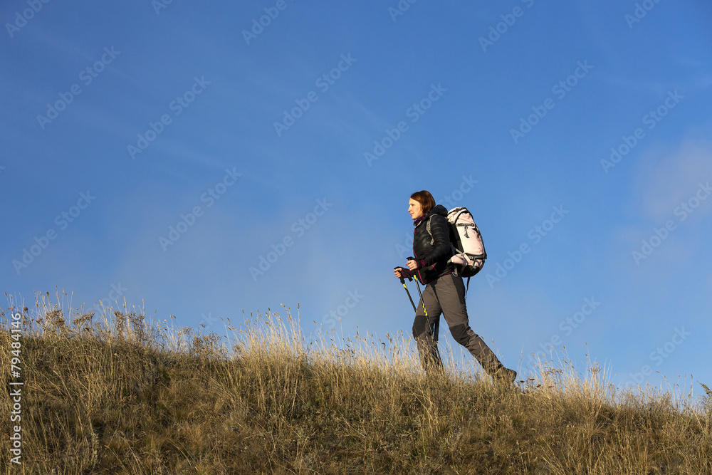 Female backpacker ascends steep hill Female backpacker ascends steep hill