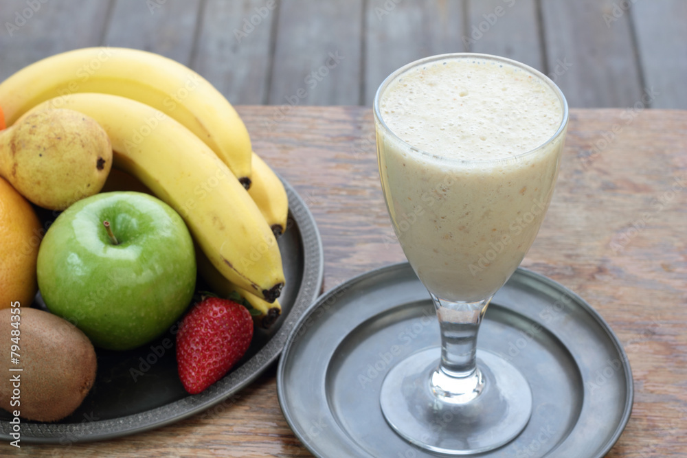 Glass full of banana milk smoothie on a tin plate. Glass full of banana milk smoothie on a tin plate.