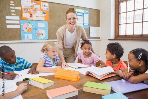 Pretty teacher helping pupils in classroom