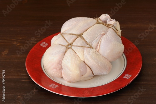 Bondage shibari raw chicken on red boarder plate on dark wood ba photo