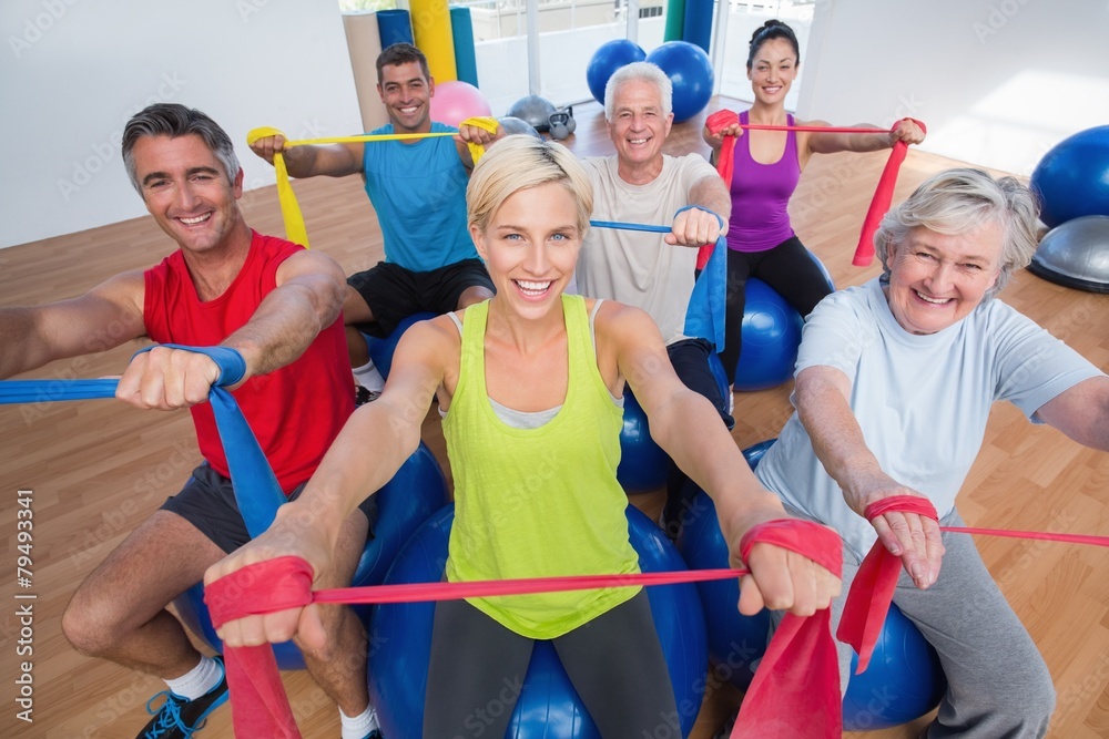 © WavebreakmediaMicro - Happy people exercising with resistance bands in gym class