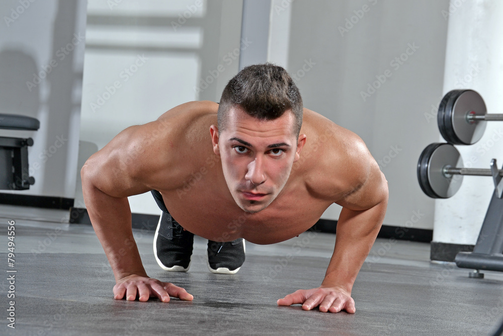 Obraz premium Hombre ejercitando haciendo flexiones en un gimnasio.