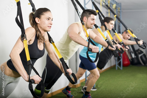People at gym doing trx elastic rope exercises photo