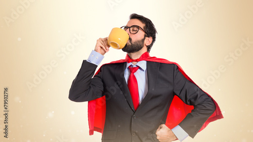 Businessman dressed like superhero drinking coffee