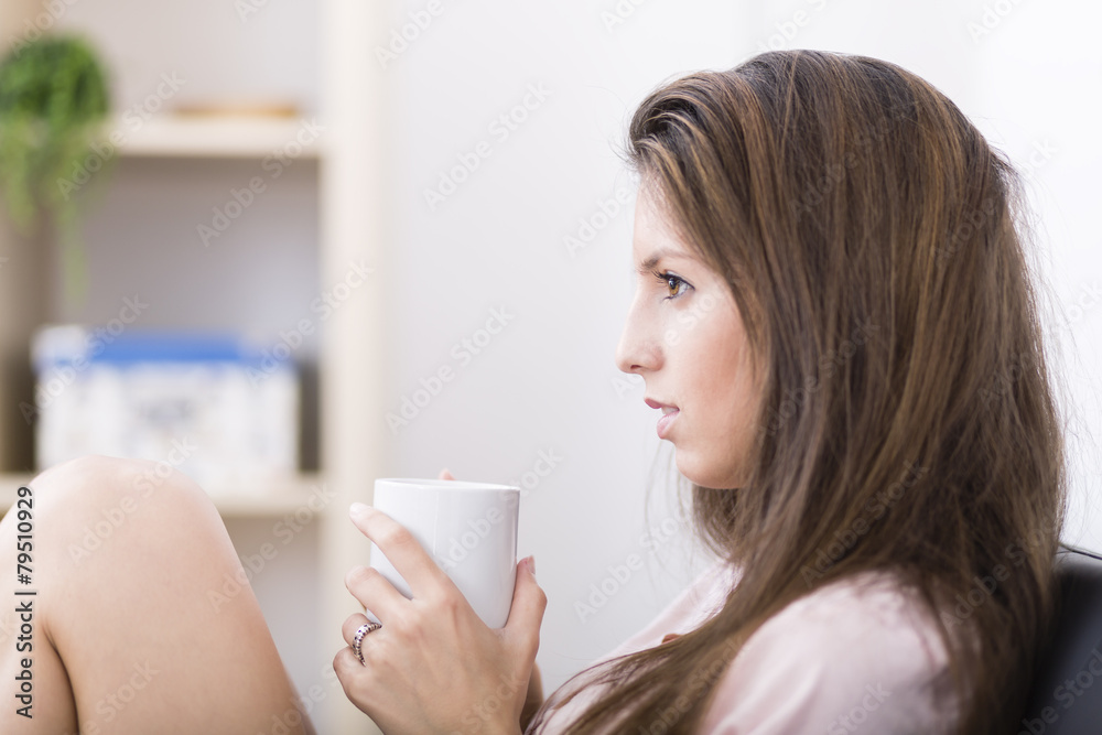 Happy young woman drinking a coffee on sofa at home Happy young woman drinking a coffee on sofa at home