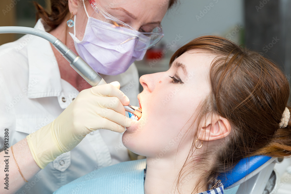 Dentist with glasses and mask treats teeth Dentist with glasses and mask treats teeth