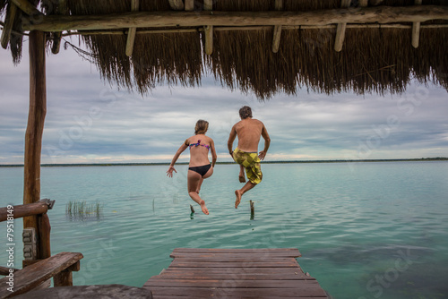 Beautiful couple in love jumping and having fun Bacalar lake. Ri