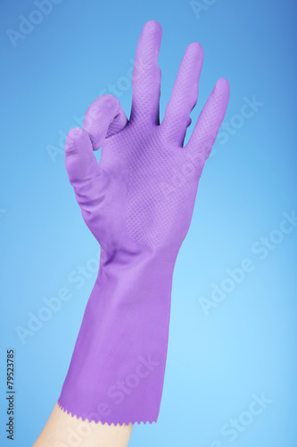 Rubber glove on hand, on blue background