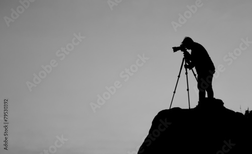 Silhouette of a photographer who shooting a sunset on the mounta