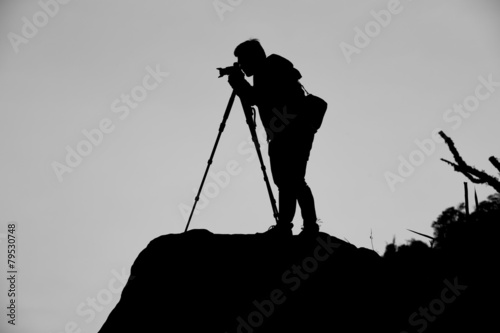 Silhouette of a photographer who shooting a sunset on the mounta