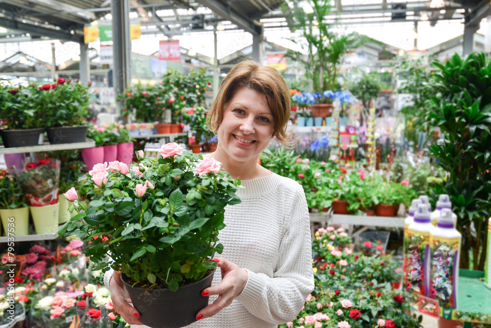 woman holding a flowers working in agreenhouse at garden center