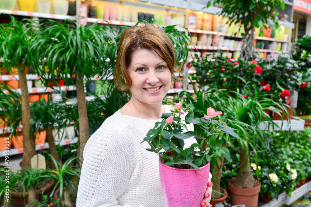 woman holding a flowers working in agreenhouse at garden center woman holding a flowers working in agreenhouse at garden center
