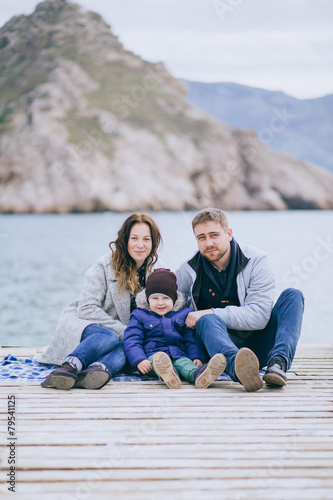 Happy family -mother, father and little son- walking in harbor