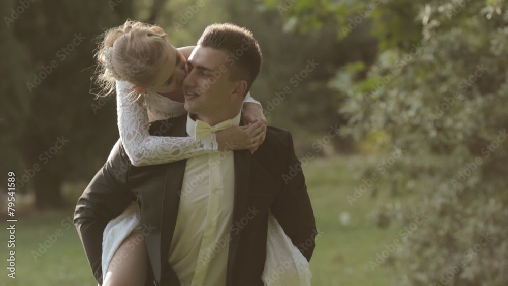 Bride jumping on the back of the groom and laughs Bride jumping on the back of the groom and laughs