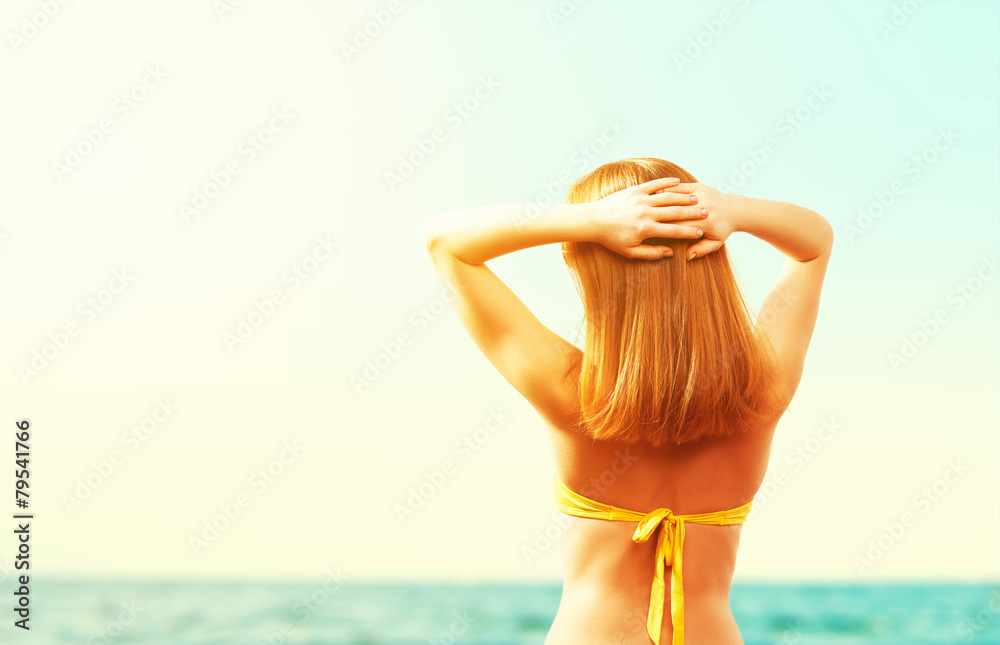 back of beautiful happy woman in yellow swimsuit on the beach in