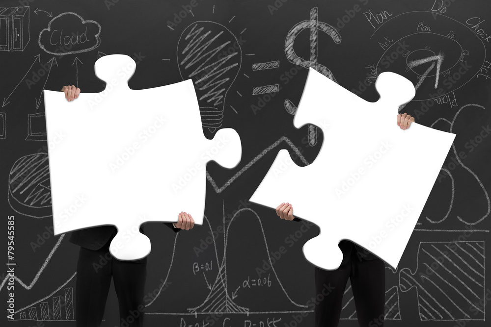 Two business people assembling blank white jigsaw puzzles with d Two business people assembling blank white jigsaw puzzles with d