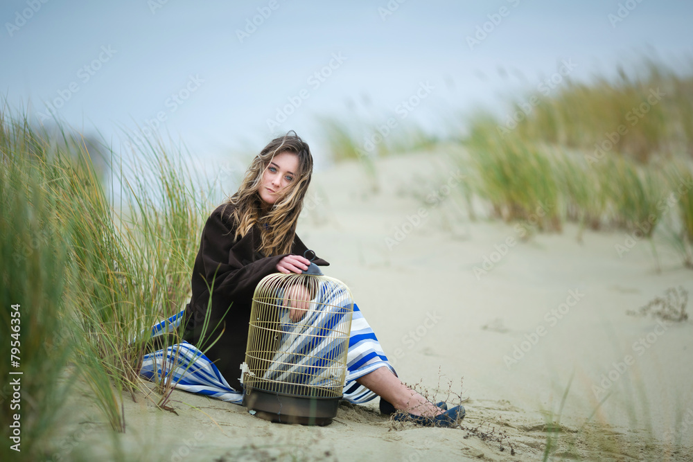 Fototapeta premium Beautiful girl with a birdcage in a dune