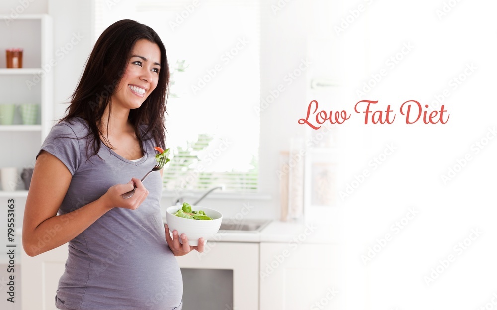 Beautiful pregnant woman holding a bowl of salad while standing Beautiful pregnant woman holding a bowl of salad while standing