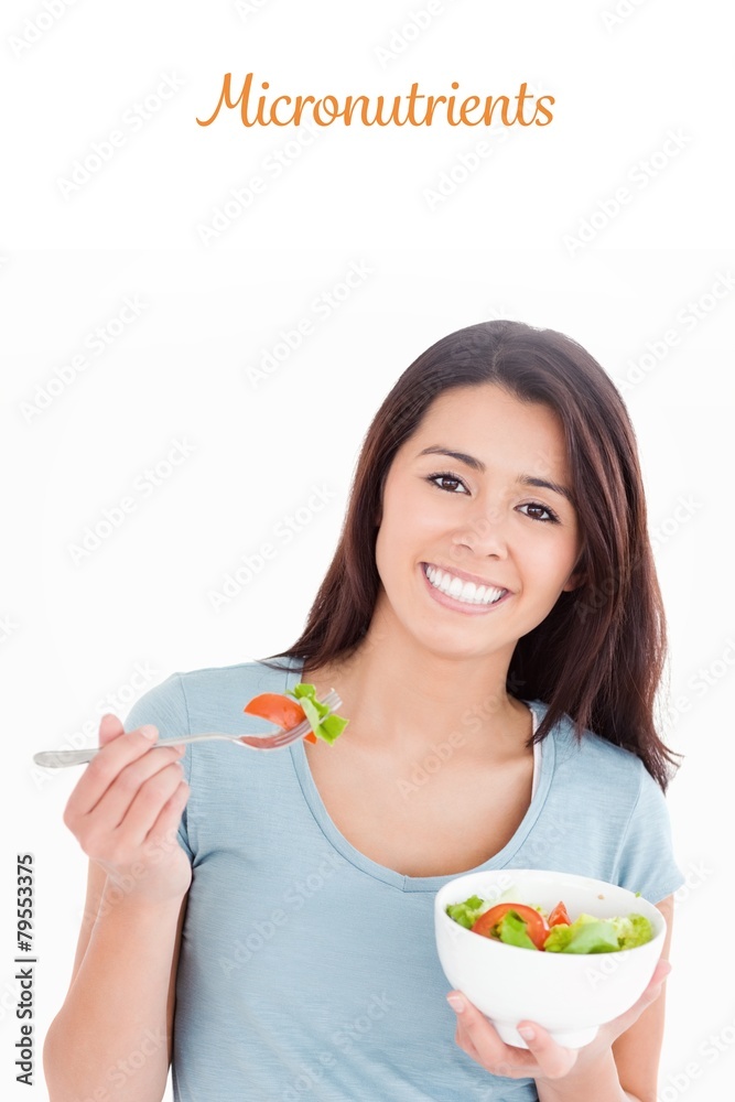 Micronutrients against good looking woman eating a bowl of salad Micronutrients against good looking woman eating a bowl of salad