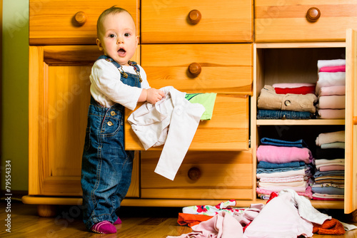 Domestic chores - baby throws out clothes photo